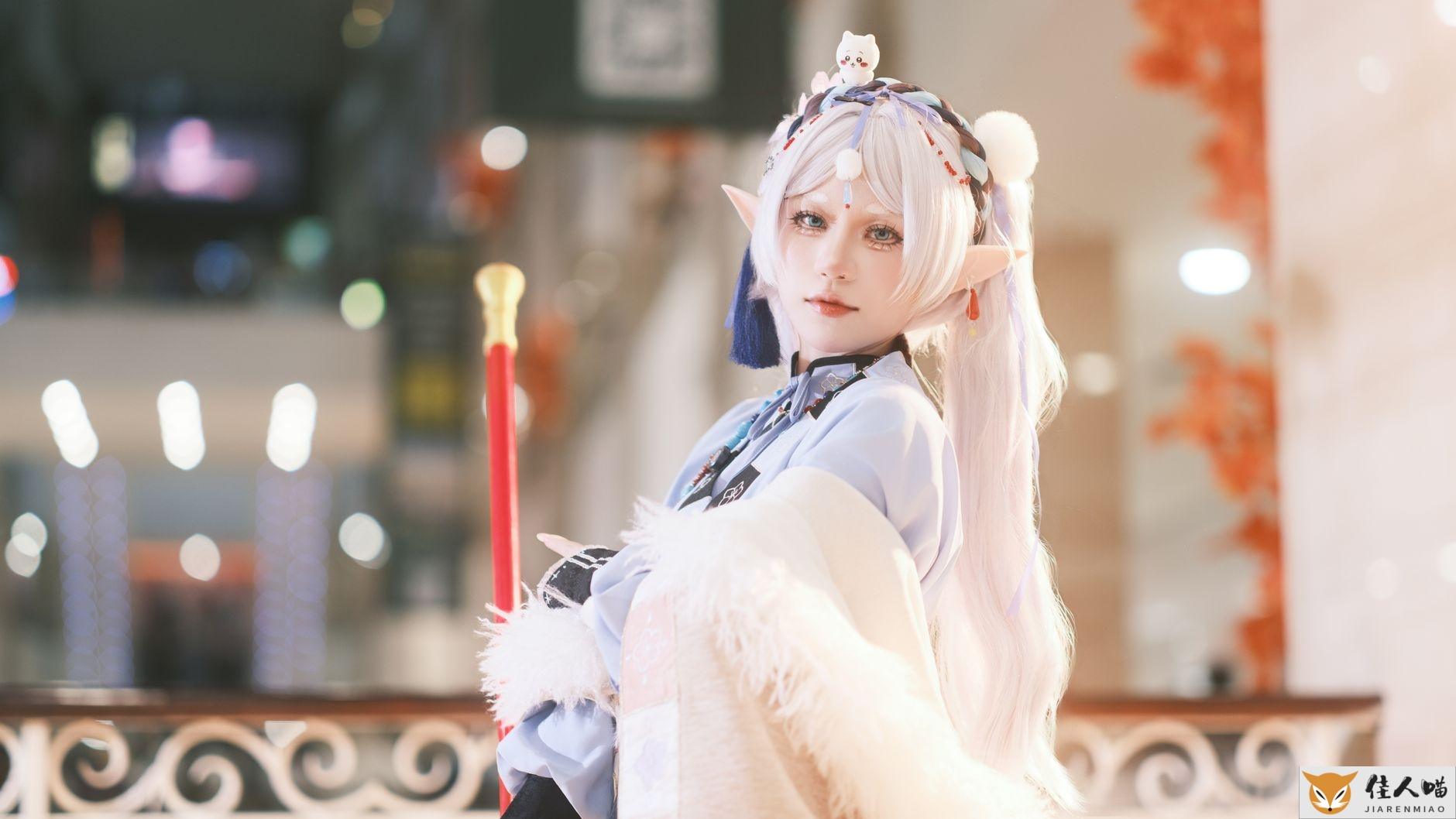 Cosplayer dressed as a fantasy elf indoors, featuring detailed costume and white hair.