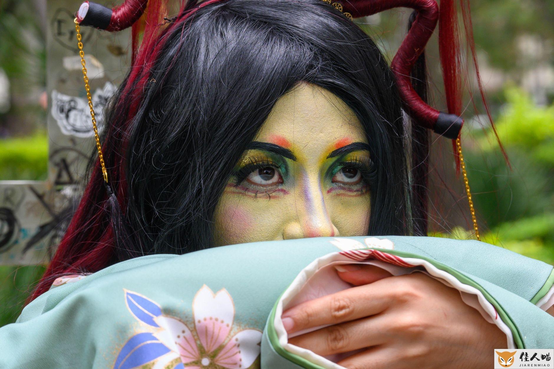 Close-up portrait of a woman in colorful traditional costume and makeup outdoors.